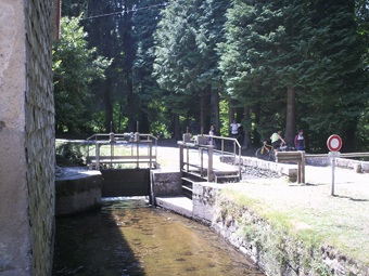 Le site de l'épanchoir du Conquet. Au premier plan : la rigole de la montagne qui vient de sortir de sa dernière tranchée et de passer sous un pont. De gauche à droite : la maison du garde, la vanne commandant l'envoi de l'eau dans la section ouest (réalisée par Vauban) de la rigole de la montagne, la vanne commandant l'envoi de l'eau dans le talweg affluent du Sor (épanchoir), le pont du chemin de service de la rigole sur la branche épanchoir.