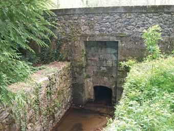 La chaussée du Lampy-Vieux : Le parement (soigné) de l'ancien barrage désaffecté avec son conduit de vidange qui est maintenant devenu le chemin normal du torrent du Lampy. Ce dernier a été canalisé par deux murs modernes qui retiennent les sédiments accumulés dans l'ancien lac.