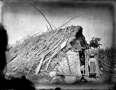 Photo sur plaque de verre - fin XIX° s. Cabane de charbonniers dans la Montagne Noire. Une jeune fillette pose devant l’objectif du photographe. On devine, sur la gauche de la photo, un homme bien habillé qui “visite” les lieux ...