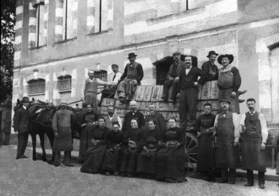     Une photo exceptionnelle (sur plaque de verre) datant de la fin du 19e siècle. Elle est prise devant la façade d’honneur de la “Fabrique GET“ et montre le départ d’une livraison de plus de 200 caisses de Pippermint GET (plus de 2400 bouteilles - les caisses sont numérotées) pour “Buenos-Ayres“. 