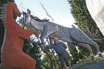    Hubert Bastouil est entouré de deux chevaux de sa  collection mesurant plus de 3 mètres de hauteur. 