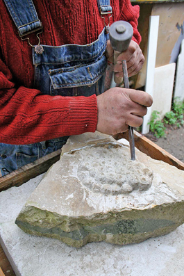    Dans cet exercice, Raymond sculpte une grappe de raisin à même la roche. Il a choisi, à dessein, une pierre de taille rectangulaire, et s’est servi d’une veine pour d’abord sculpter le sarment, puis les grains. Ses seuls outils sont un burin et un marteau.  
