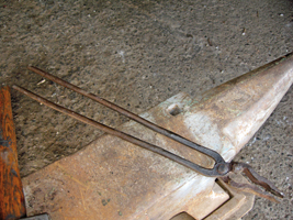 Les tenailles de forge permettaient à l’artisan de saisir les pièces métalliques rougies dans l’âtre. De longs manches destinés à le préserver de la chaleur émise par la pièce autorisaient davantage de dextérité.